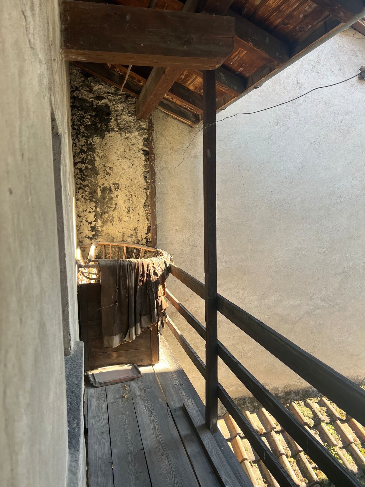 Il ballatoio in legno di una casa abbandonata, prima della riparazione