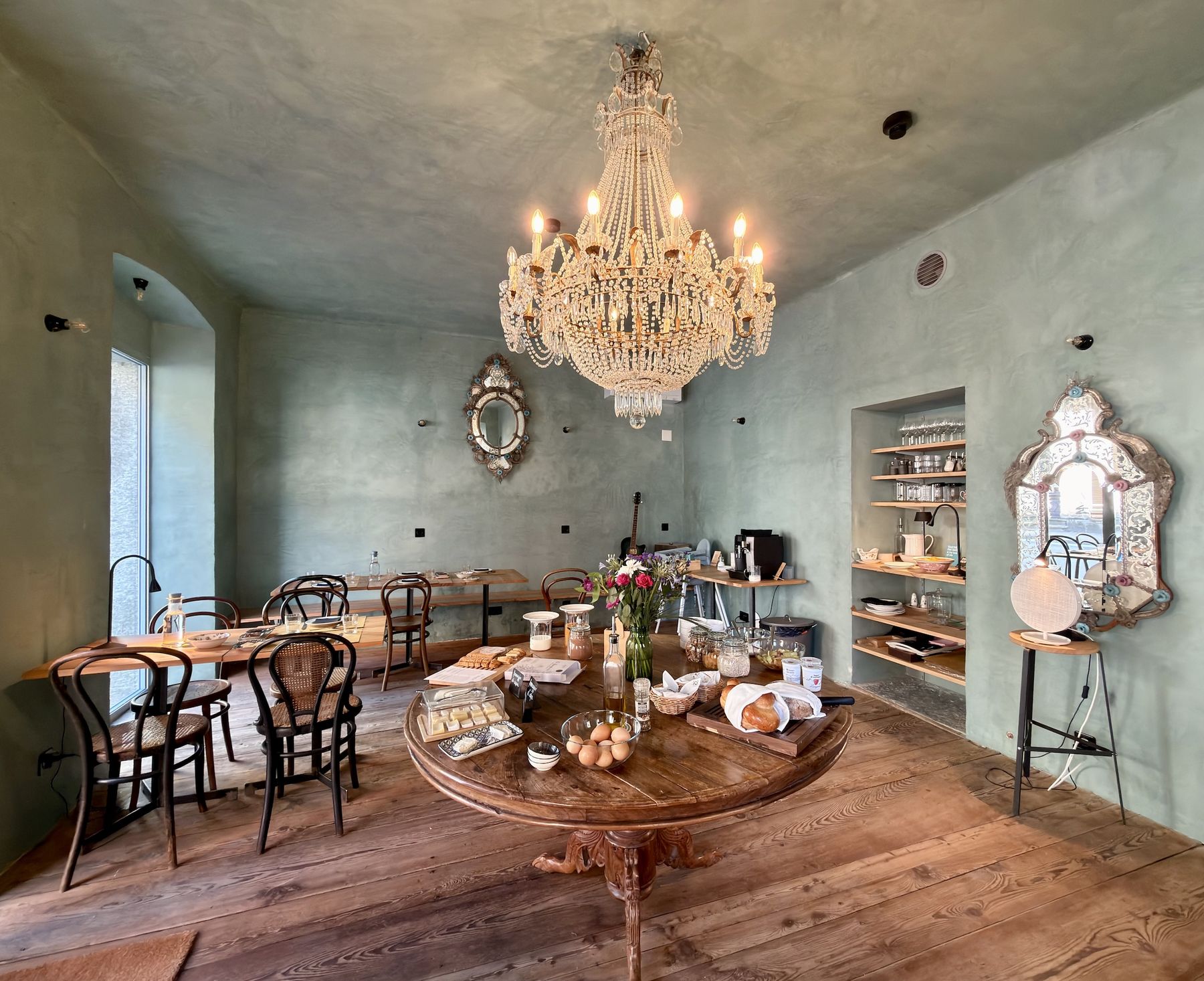 La sala di Casa Piumogna con il lampadario di cristallo e il tavolo rotondo